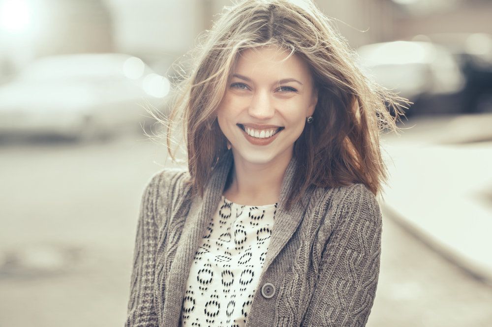 Laughing woman posing on street with hair blowing in wind