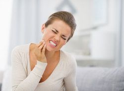 Woman grimacing and clutching jaw in pain